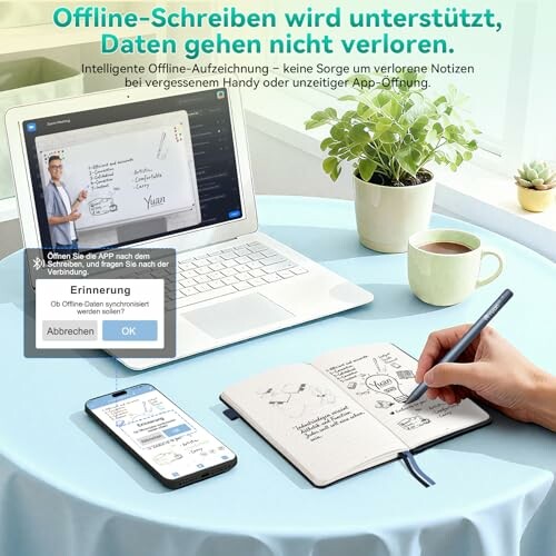 Mann schreibt Notizen in ein Buch mit einem Tablet und Laptop auf einem Tisch.