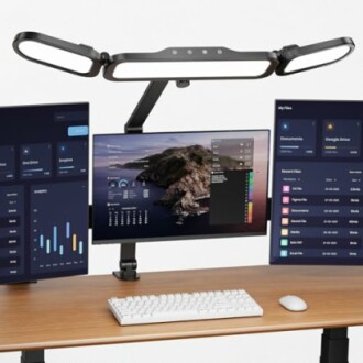 Dreifacher Monitor-Setup mit Schreibtischlampe.